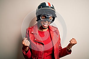 Young African American afro motorcyclist woman with curly hair wearing motorcycle helmet very happy and excited doing winner