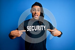 Young african american afro safeguard man with dreadlocks wearing security uniform very happy pointing with hand and finger