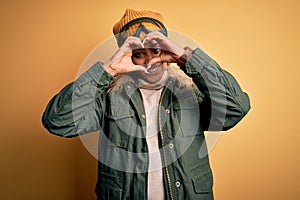 Young african american afro skier girl wearing snow sportswear and ski goggles Doing heart shape with hand and fingers smiling