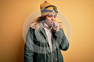 Young african american afro skier girl wearing snow sportswear and ski goggles feeling unwell and coughing as symptom for cold or