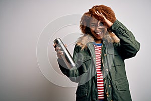 Young African American afro tourist woman with curly hair holding thermo with water with happy face smiling doing ok sign with