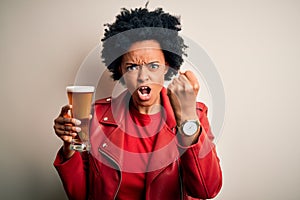 Young African American afro woman with curly hair drinking glass of beer with alcohol annoyed and frustrated shouting with anger,