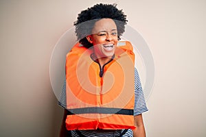 Young African American afro woman with curly hair wearing orange protection lifejacket winking looking at the camera with sexy