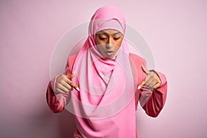 Young African American afro woman wearing muslim hijab over isolated pink background Pointing down with fingers showing