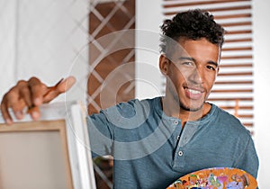 Young African-American artist painting picture at home