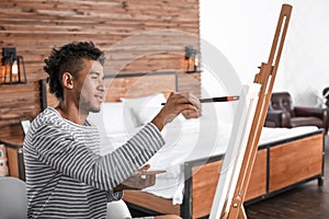 Young African-American artist painting picture at home