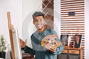 Young African-American artist painting picture at home