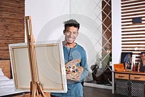 Young African-American artist painting picture at home