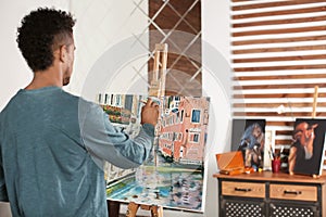 Young African-American artist painting picture at home