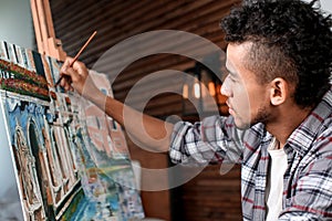 Young African-American artist painting picture in workshop