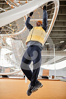 Young African American athlete in activewear pull up exercise