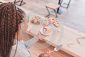 Young african american barista holding a plate with piece