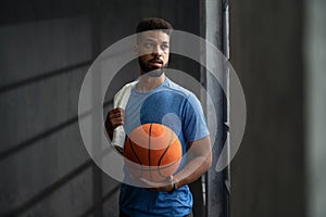 Young African American basketball player standing indoors at gym.