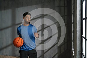 Young African American basketball player standing indoors at gym.