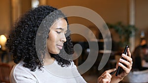 Young African American Black Woman Having Fun Using Smart Phone Technology In Cafe