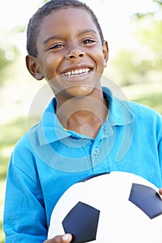 Young African American Boy Holding Football In Park