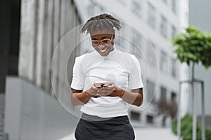 Young african american business lady in casual wear checking work emails outdoors.