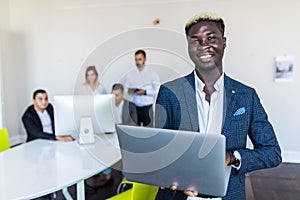Young African-American Business leader standing in front of business team smiling