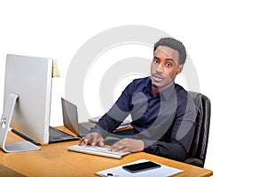 Young African American business man sitting at his office desk and typing on computer