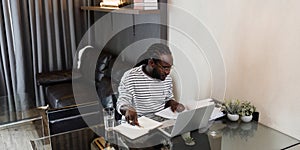 Young African American business man working with laptop and document on desk at home. work from home concept