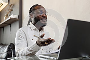 Young African American business man working with laptop and document on desk and talking on mobile at home