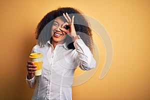 Young african american business woman with afro hair drinking coffee from take away cup with happy face smiling doing ok sign with