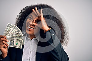 Young african american business woman with afro hair holding cash dollars banknotes with happy face smiling doing ok sign with