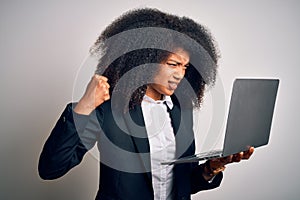 Young african american business woman with afro hair using computer laptop from job annoyed and frustrated shouting with anger,