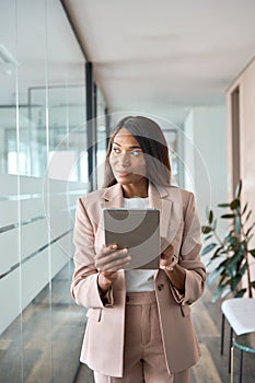 Young African American business woman manager using tablet in office thinking.