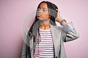 Young african american business woman standing over pink isolated background confuse and wondering about question
