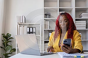 Young African American business woman talking on the phone and taking notes while working in the office