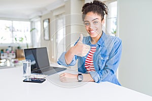 Young african american business woman working using computer laptop doing happy thumbs up gesture with hand