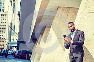 Young African American Businessman with beard, short hair, texting on cell phone outside in New York City