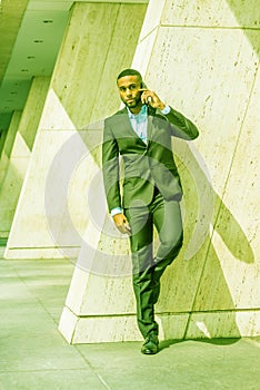 Young African American Businessman with beard talking on cell phone outside office in New York