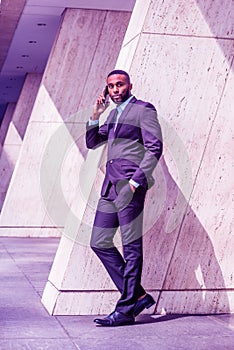 Young African American Businessman with beard talking on cell phone outside office in New York