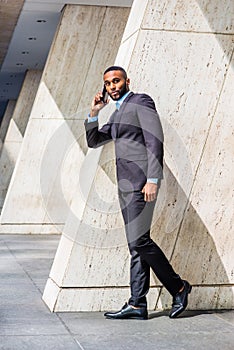 Young African American Businessman with beard talking on cell phone outside office in New York