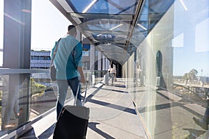 Young african american businessman with luggage walking behind businesswoman at airport corridor