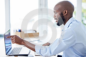 Young african american businessman pointing his finger and working on a laptop in an office alone at work. One male
