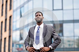 Young african american businessman posing by office center, happy male entrepreneur having break and walking outdoors