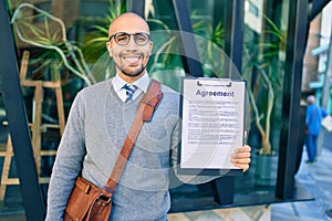 Young african american businessman smiling happy holding clipboard with agreement document at the city