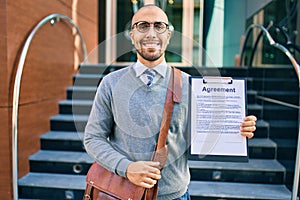 Young african american businessman smiling happy holding clipboard with agreement document at the city