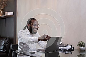 Young African American businessman spends his free time working from home on his laptop.