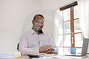 Young African American businessman uses laptop to work on white wooden table in office room.