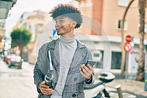 Young african american businessman using smartphone holding bottle of water at the city