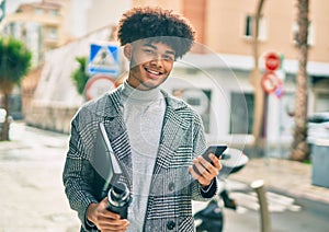 Young african american businessman using smartphone holding bottle of water at the city