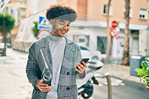 Young african american businessman using smartphone holding bottle of water at the city