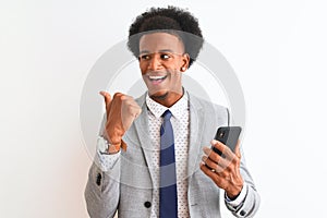 Young african american businessman using smartphone over isolated white background pointing and showing with thumb up to the side