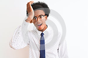 Young african american businessman wearing tie and glasses over isolated white background surprised with hand on head for mistake,