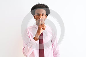 Young african american businessman wearing tie standing over isolated white background asking to be quiet with finger on lips