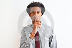 Young african american businessman wearing tie standing over  white background asking to be quiet with finger on lips